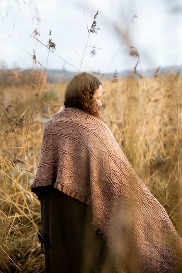 image of a brown shawl being worn on a woman in a field with tall grasses