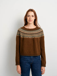 Woman wearing a brown sweater with a patterned yoke against a white background