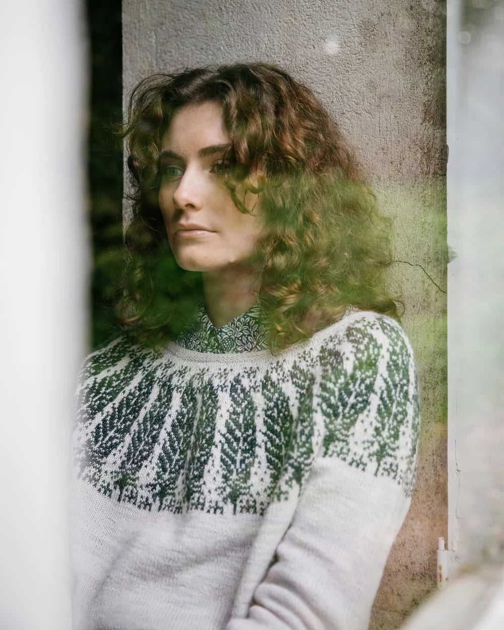a colourwork sweater being worn by the designer in whites with green