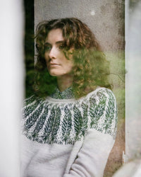 a colourwork sweater being worn by the designer in whites with green