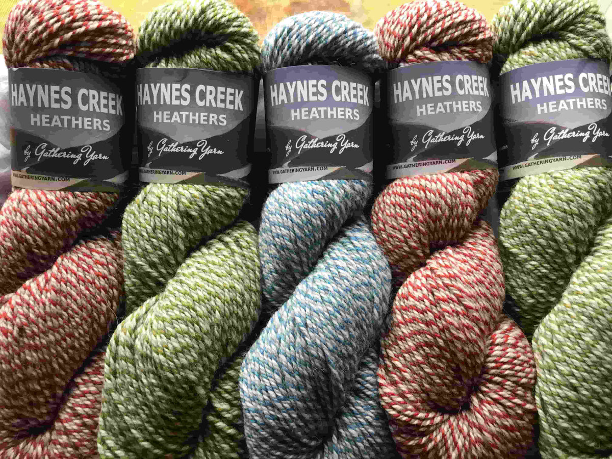 Five skeins of Haynes Creek Heathers yarn with labels on a textured surface.