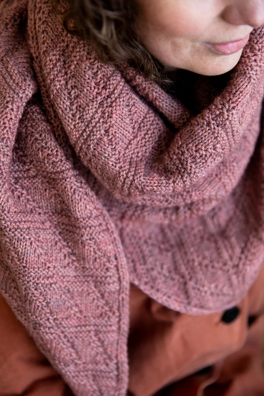 close up of a knit shawl or triangle scarf being worn on a person
