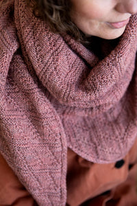 close up of a knit shawl or triangle scarf being worn on a person