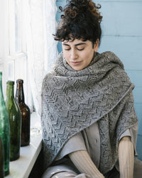 a shawl wrapped around a person sitting in front of a window