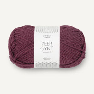 A single skein of Peer Gynt yarn in a deep plum purple color, wrapped with a white paper label, on a light off-white background.