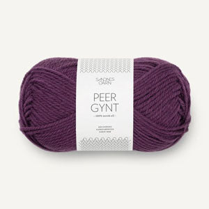 A skein of deep purple Peer Gynt yarn with a white paper label, shown against a light off-white background.