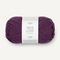 A skein of deep purple Peer Gynt yarn with a white paper label, shown against a light off-white background.
