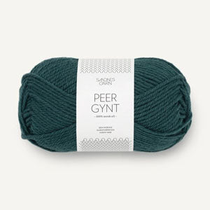 A skein of Peer Gynt yarn in a deep teal green color, wrapped with a white paper label, on a light off-white background.
