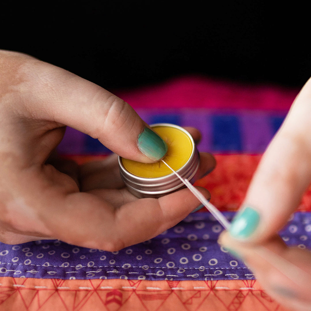 a persons hands using showing how to pull the thread across the open tin of thread gloss
