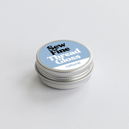 Sew Fine Thread Gloss container with blue label on a light gray background