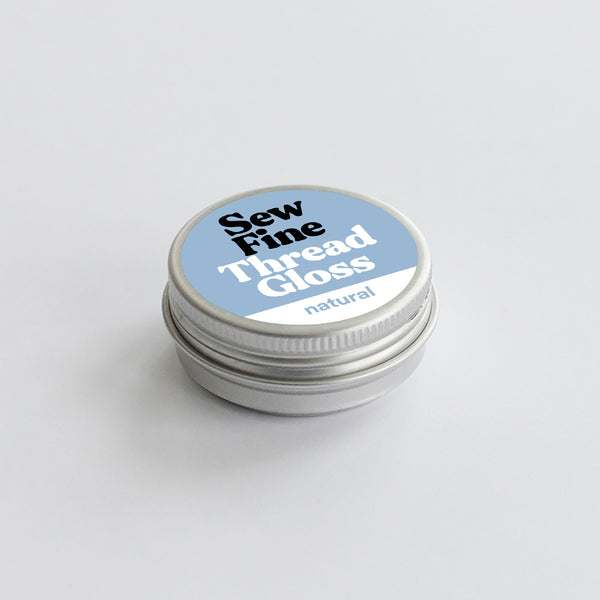 Sew Fine Thread Gloss container with blue label on a light gray background
