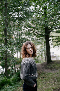 the designer wearing a colourwork sweater in the forest