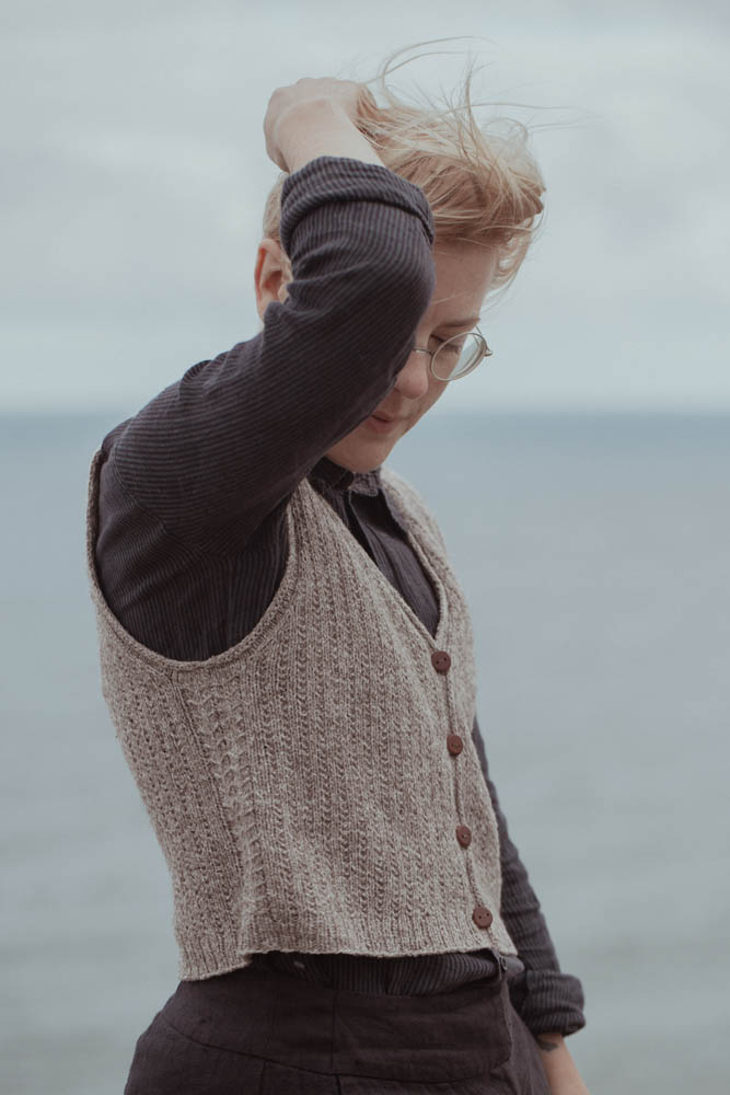 Person wearing a knitted vest by the sea