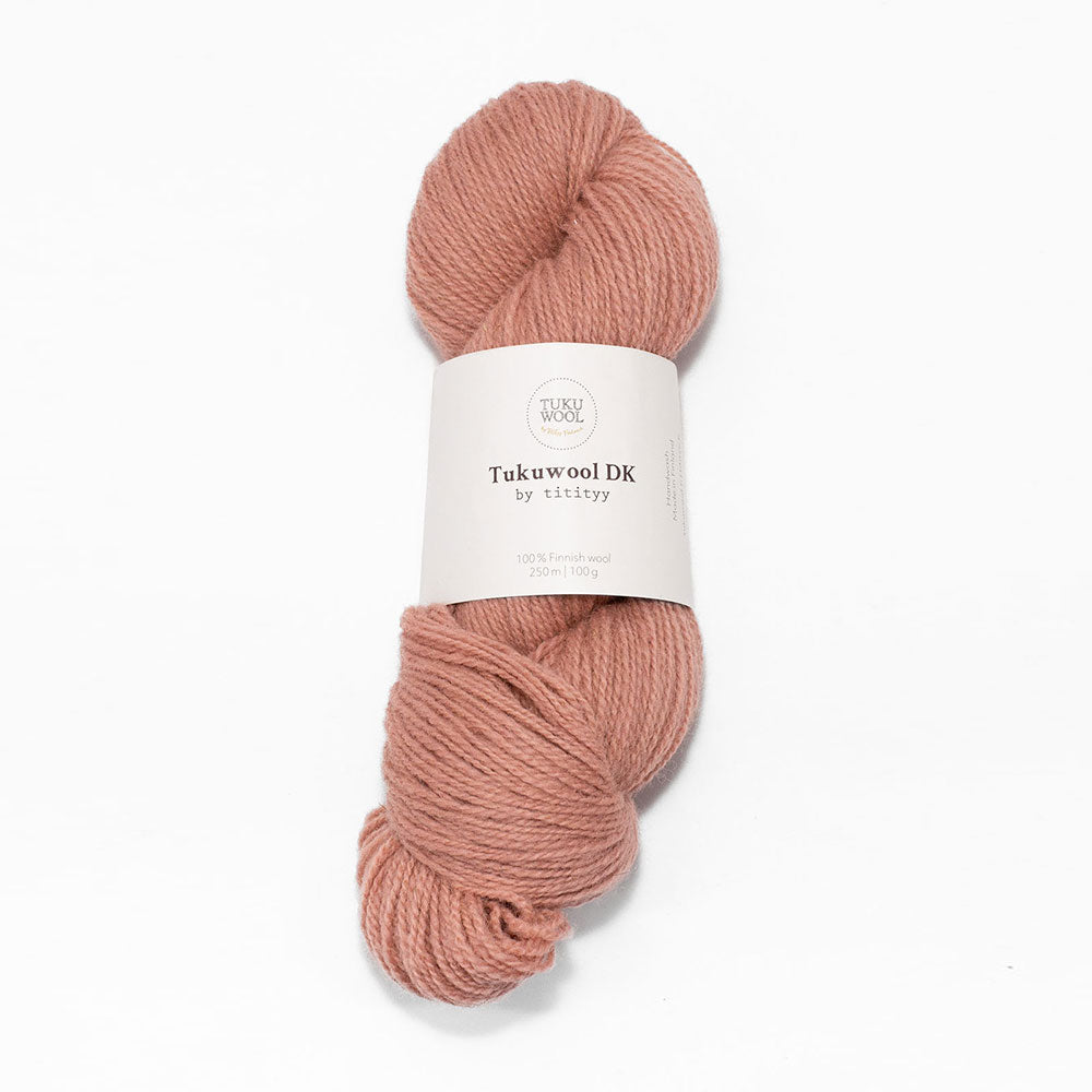 A skein of dusty rose pink Tuku wool DK yarn with a white paper label, centered on a clean white background.