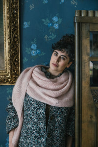 person wearing a shawl and leaning up against a piece of furniture