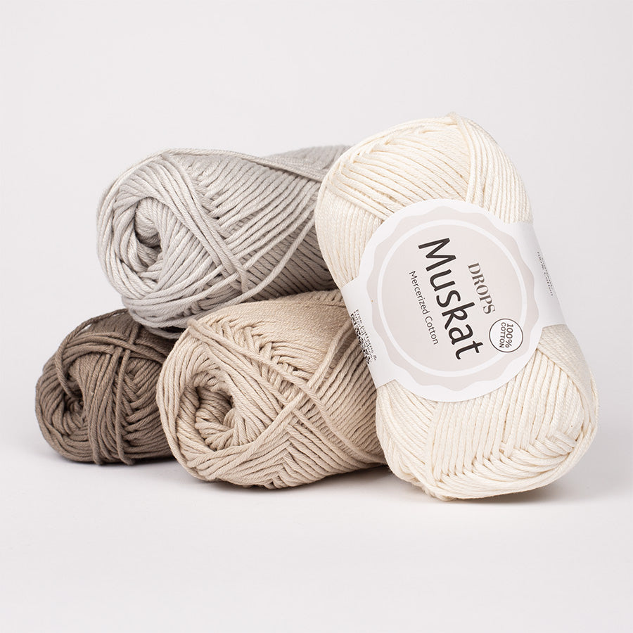 Three skeins of yarn in beige, brown, and gray with a 'Muskat' label on a light gray background.