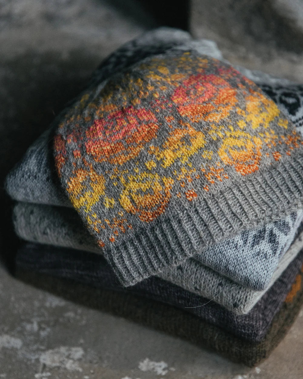 colour work hat on top of a folded pile of knit sweaters