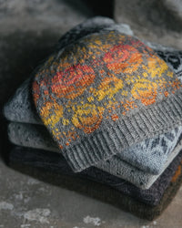 colour work hat on top of a folded pile of knit sweaters